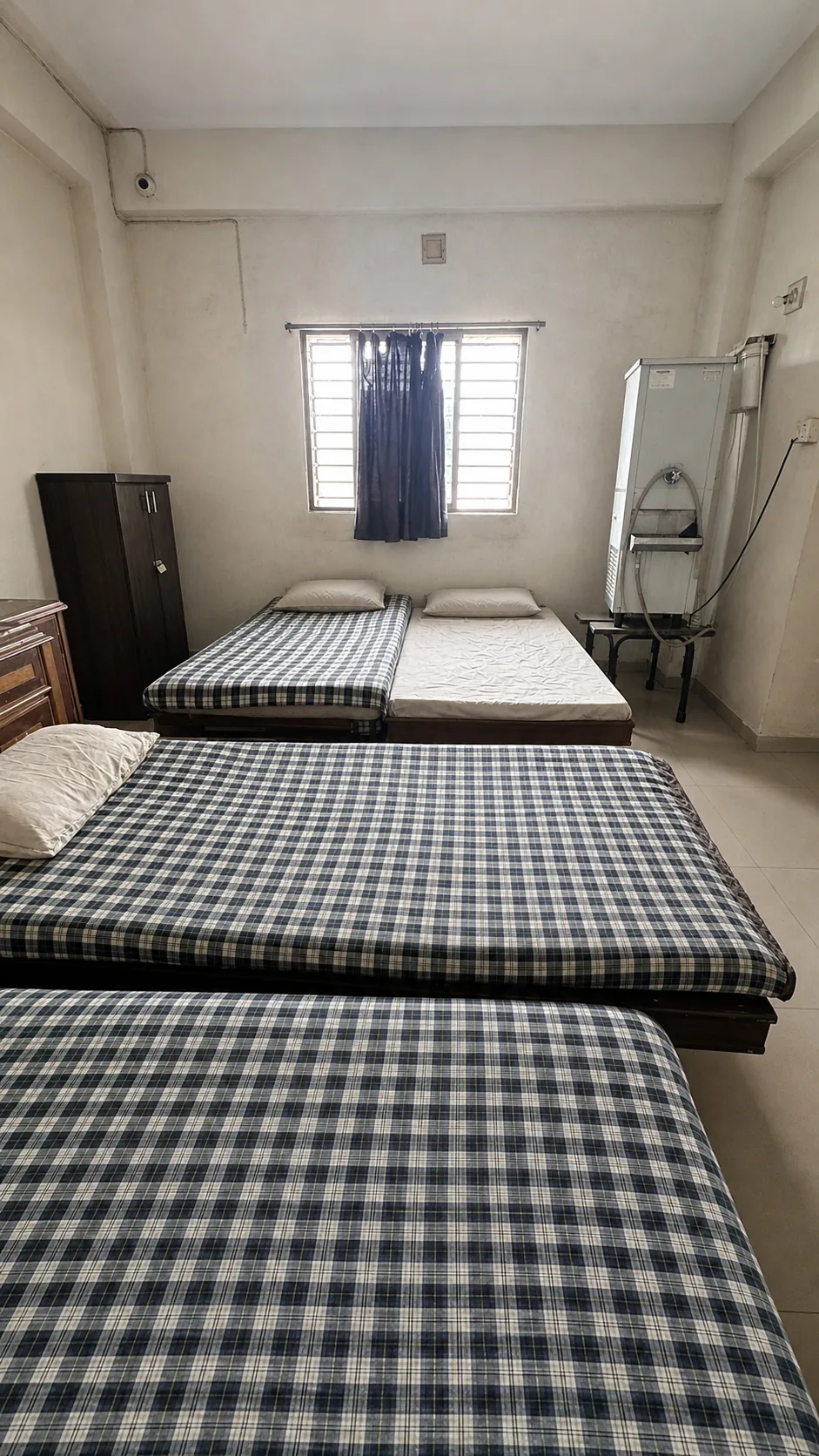Multi-bed shared room with checked bedding, windows and storage