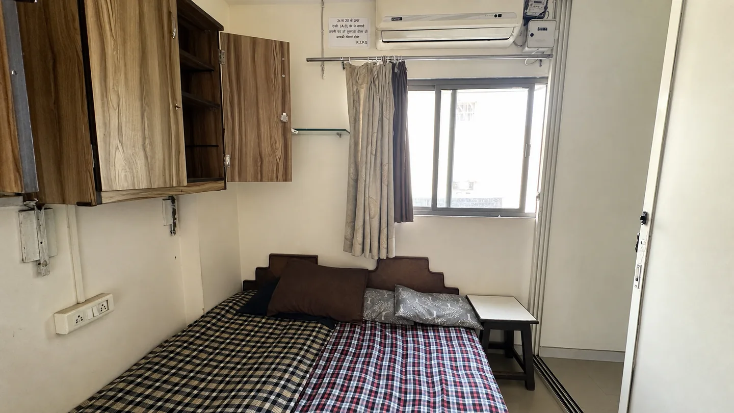 Wide alternate view of a furnished room with checked bedding