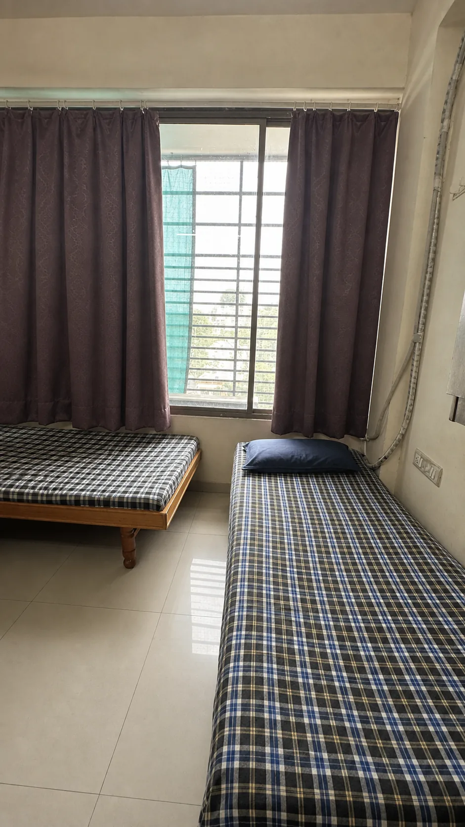 Shared room with checked bedding, purple curtains and a wide window