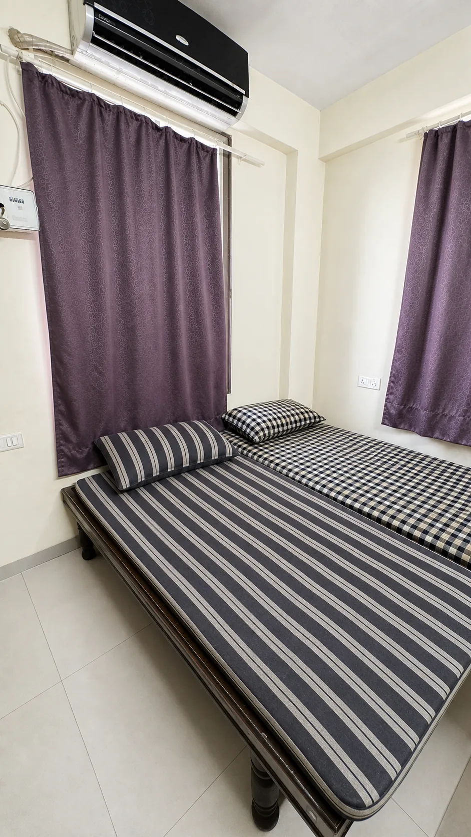 Furnished PJ PG room with striped beds, curtains and a wall unit