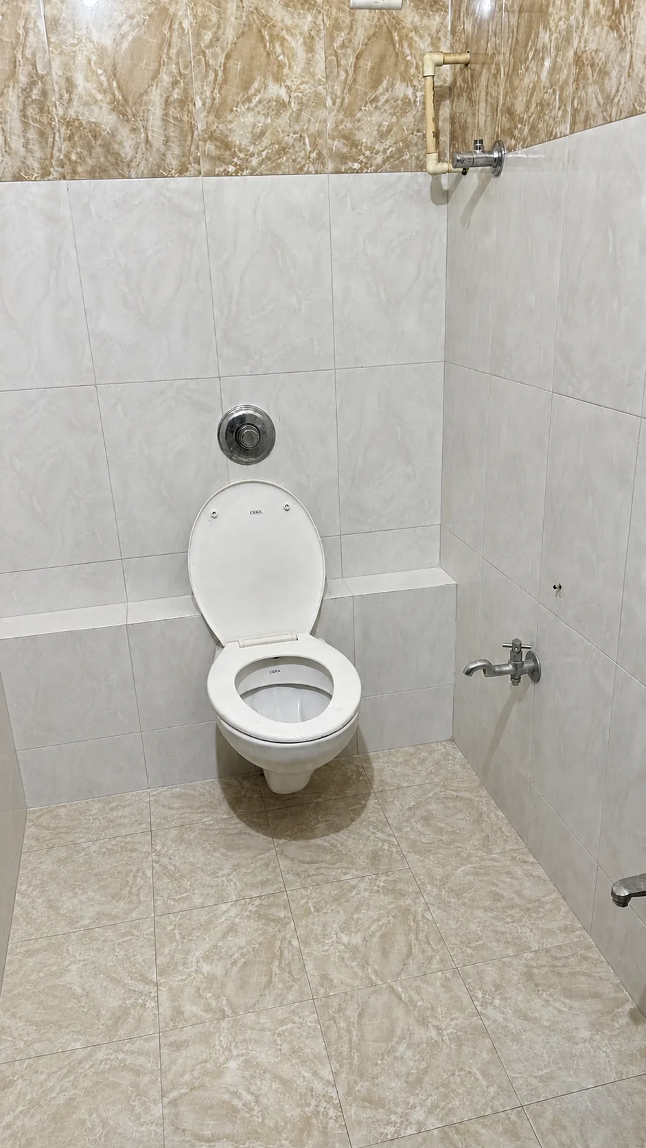 Tiled PJ PG washroom with a wall-mounted toilet and taps