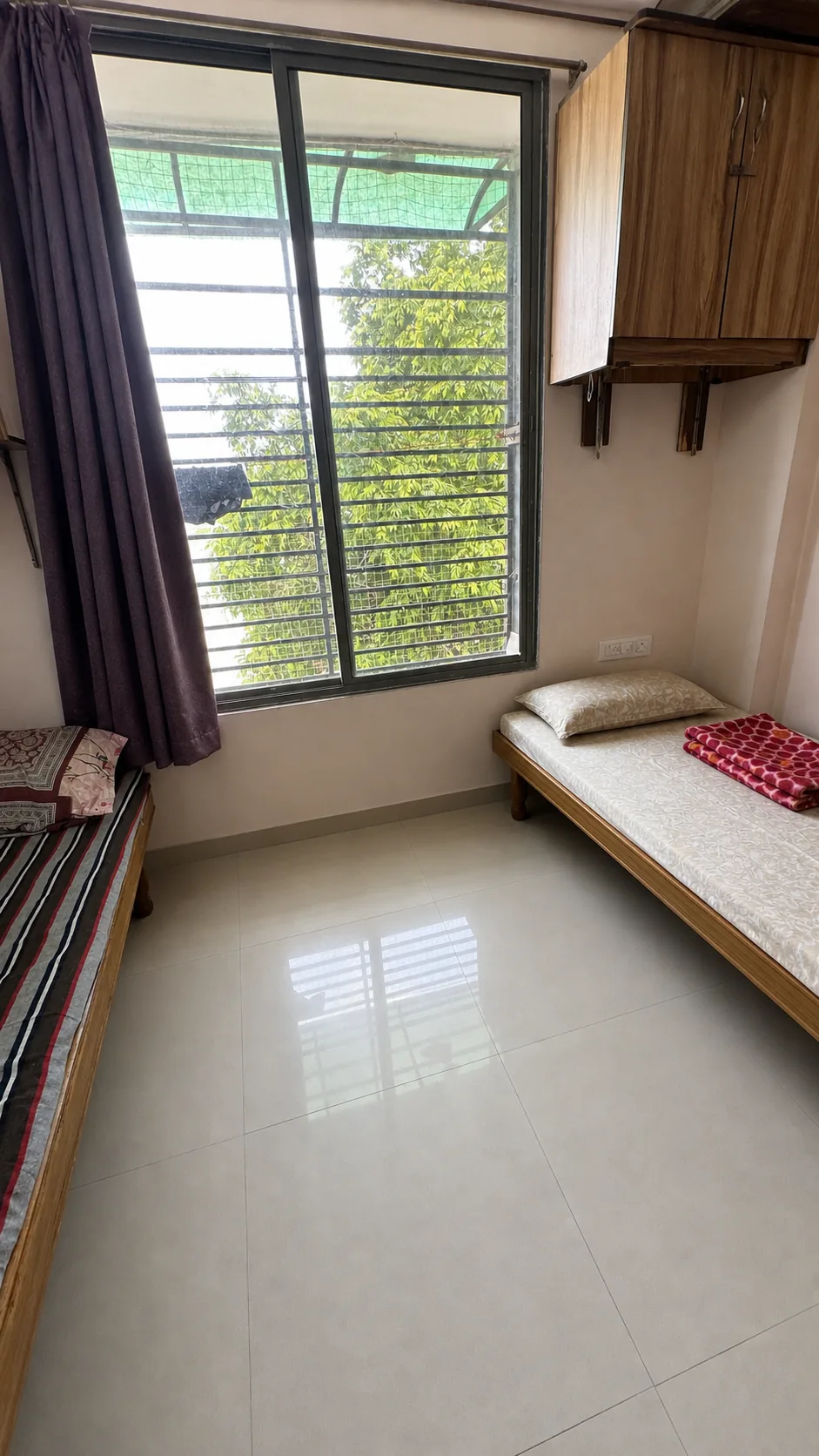 Two-bed PG room with a large grilled window and open floor space